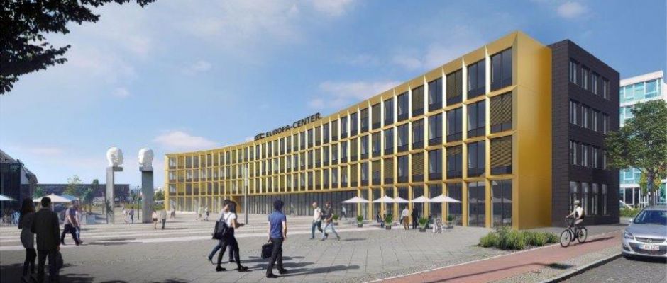 Moderne Architektur des Europa Centers mit goldenen Akzenten und Fußgängern auf dem Platz. Bäume und Fahrräder sichtbar.