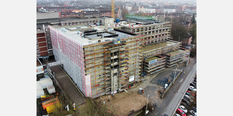 Bauprojekt eines mehrstöckigen Gebäudes mit Gerüst und Bauarbeiten in städtischer Umgebung.