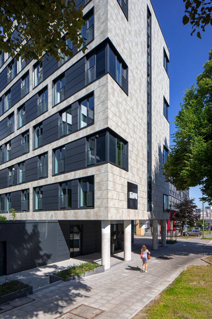 Moderne Architektur eines mehrstöckigen Gebäudes mit großen Fenstern und einem klaren, minimalistischen Design.