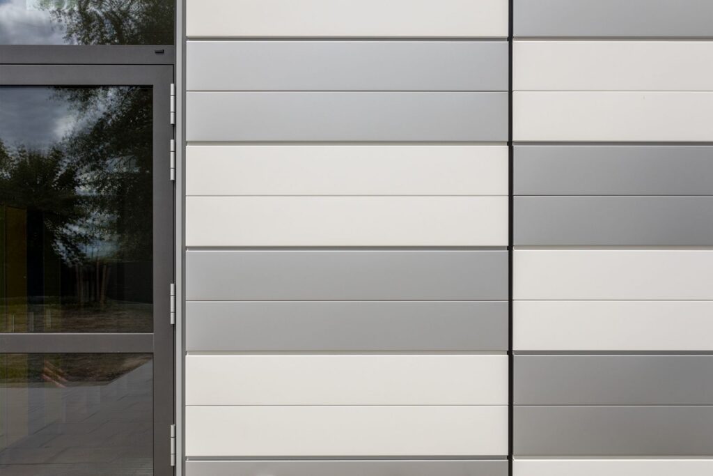 Fassade mit horizontalen Platten in Grau- und Weißtönen, neben einer großen Glasschiebetür.
